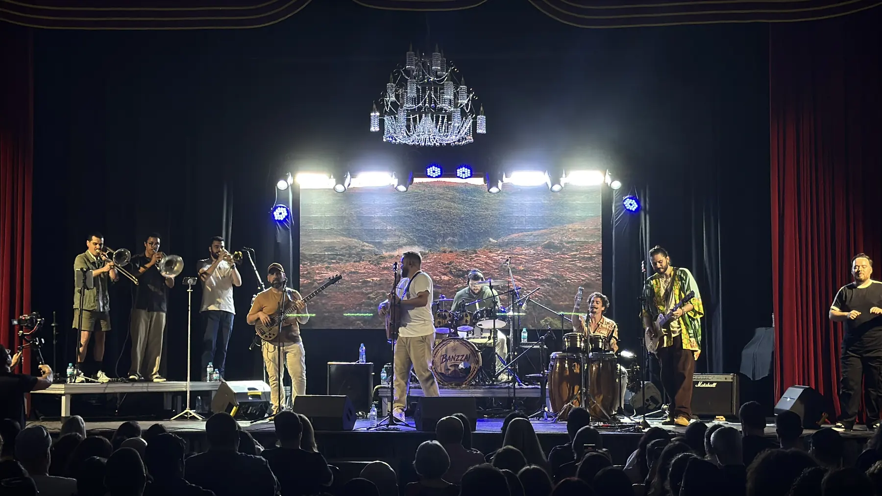 Banda no palco, com paisagem de terra vermelha projetada no telão