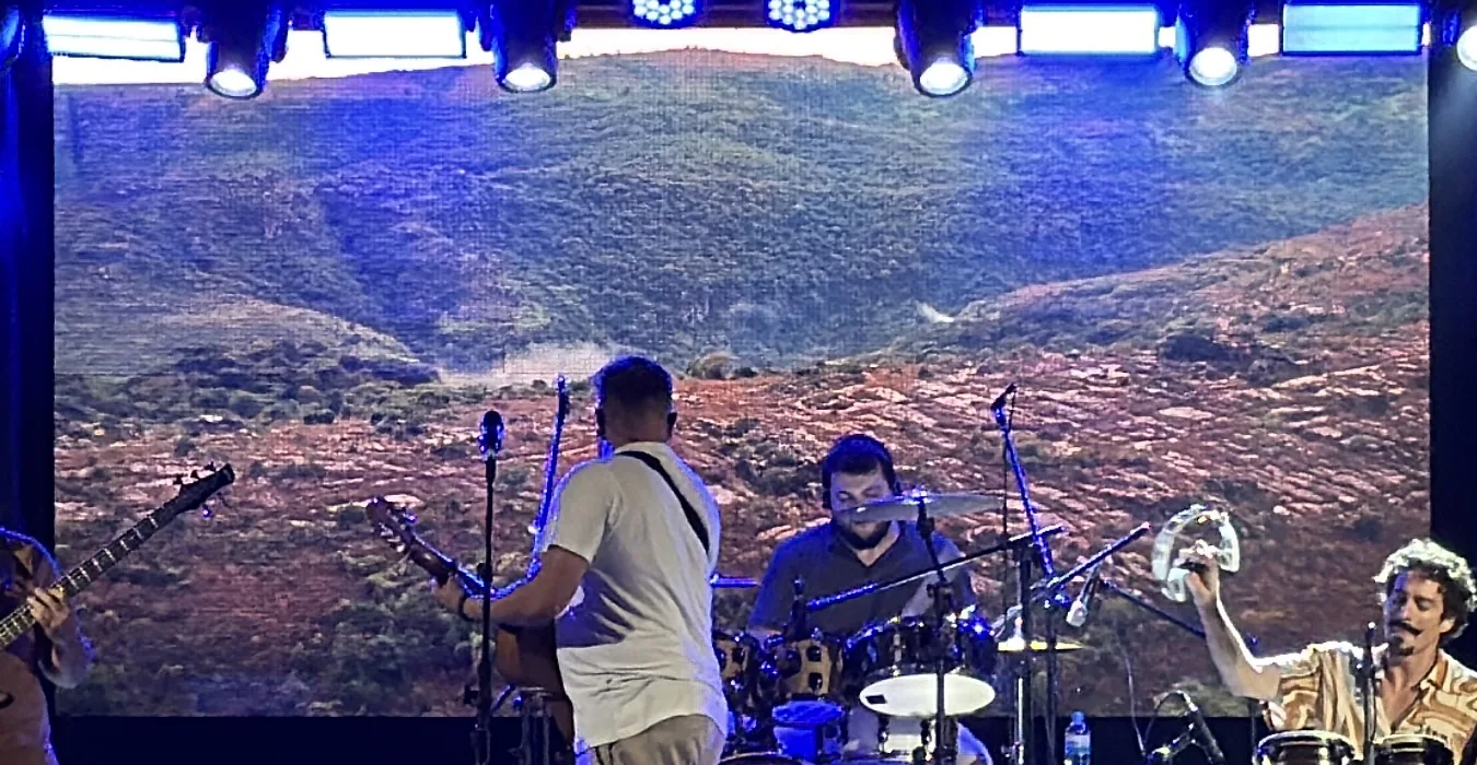 Músicos da Banzzai no palco diante de uma paisagem de terra vermelha projetada